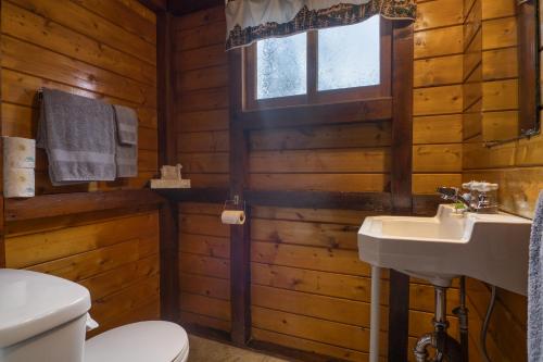 baño con aseo y lavamanos en una cabaña de madera en Timbers Resort en Fairmont Hot Springs
