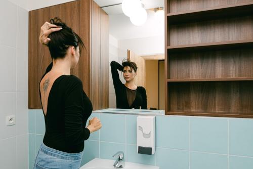 una mujer parada frente a un espejo de baño en Flora Cozy Apartment, en Bratislava