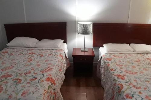 um quarto com 2 camas e um candeeiro numa mesa de cabeceira em Regal Motel em Timmins