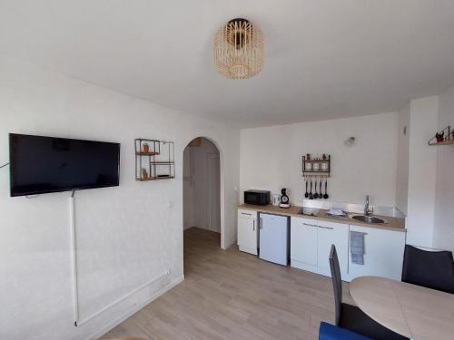 a kitchen with white cabinets and a flat screen tv at Mon beau studio in Vesoul