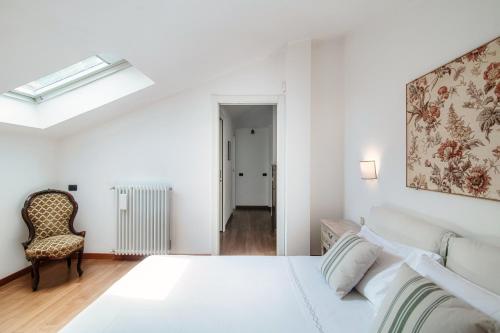 a white bedroom with a bed and a chair at I D'A Charming Penthouse - LAKE VIEW in Como