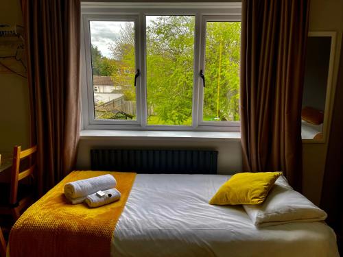 a bed with two towels on it in front of a window at Hollybush Guest House in Oxford