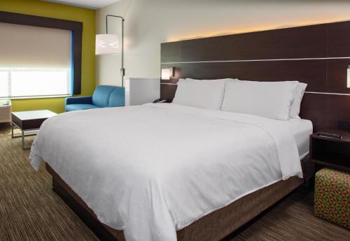 a bedroom with a large white bed and a blue chair at Holiday Inn Express & Suites - El Paso North, an IHG Hotel in El Paso