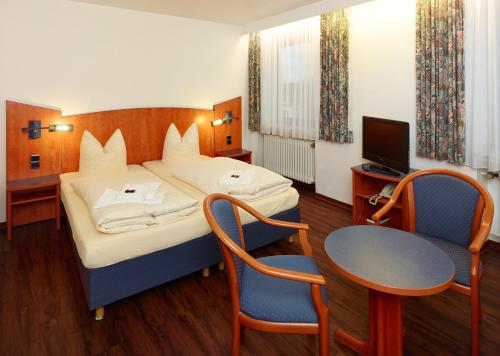 a bedroom with a bed and a table and a television at Hotel Stadt Daun in Daun