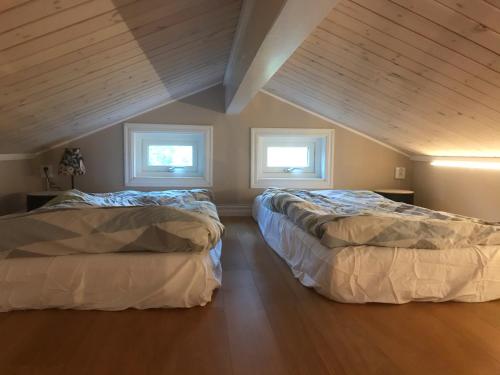 two beds in a room with two windows at Välutrustad stuga med vacker sjöutsikt in Urshult