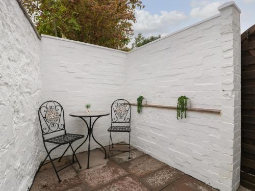 a patio with two chairs and a table against a white wall at The Cwtch in Abergavenny