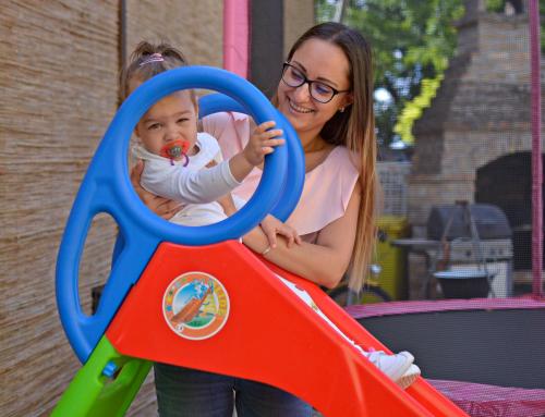 a woman holding a baby playing with a pair of scissors at R.Gold Apartman in Makó