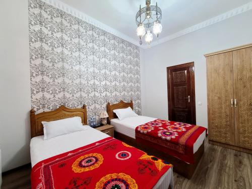 1 Schlafzimmer mit 2 Betten und einem Kronleuchter in der Unterkunft Oybinokh hotel in Buxoro