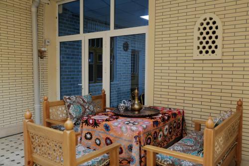 einen Tisch und Stühle auf einer abgeschirmten Veranda mit einem Tisch und Stühlen in der Unterkunft Oybinokh hotel in Buxoro