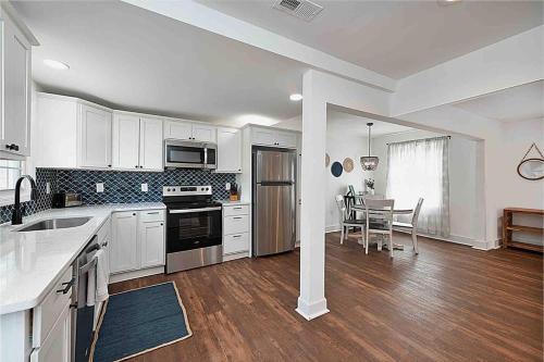 a kitchen with white cabinets and a table in it at Millcreek Cottage Minutes from Downtown Wilmington in Leland