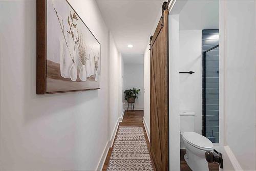 a bathroom with a toilet and a hallway at Millcreek Cottage Minutes from Downtown Wilmington in Leland