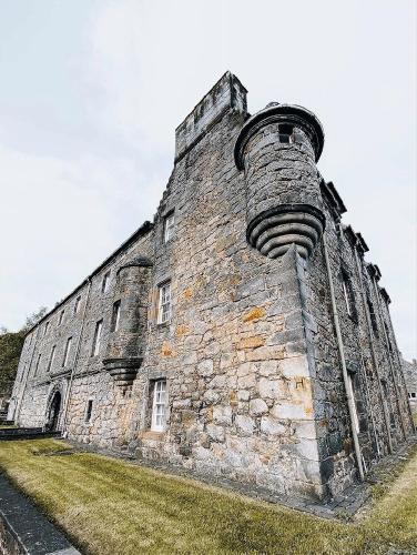 an old stone building with a chimney on the side of it at Menstrie Castle Stay in Stirling
