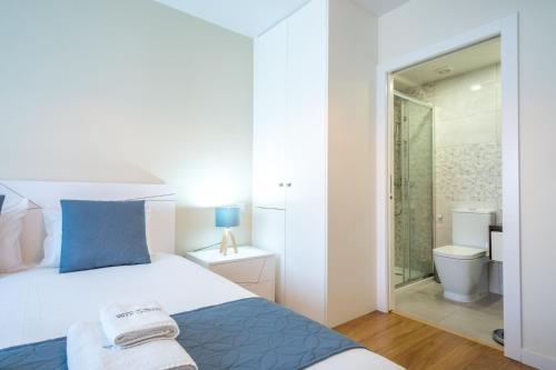 a bedroom with a bed and a bathroom with a shower at Villa Tavares Suítes in Arouca