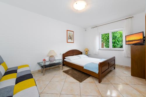 sypialnia z łóżkiem, telewizorem i kanapą w obiekcie Apartments Melita w Crikvenicy
