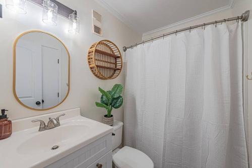a bathroom with a sink and a toilet and a mirror at Hang Ten Hideaway, pool, Condo, Parking, payment due upon booking Host will reach out once you book in Carolina Beach