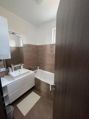 baño con lavabo, bañera y puerta en BRL Apartman, en Nyíregyháza