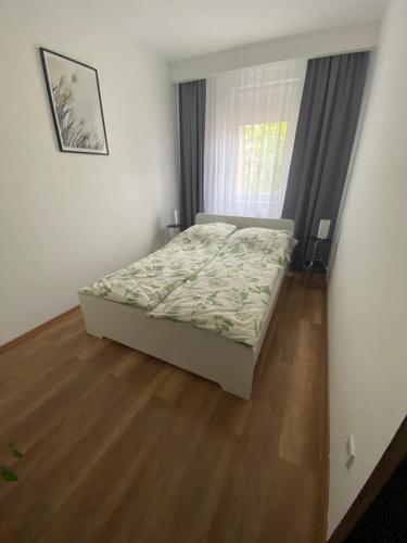 a bedroom with a bed and a wooden floor at BRL Apartman in Nyíregyháza