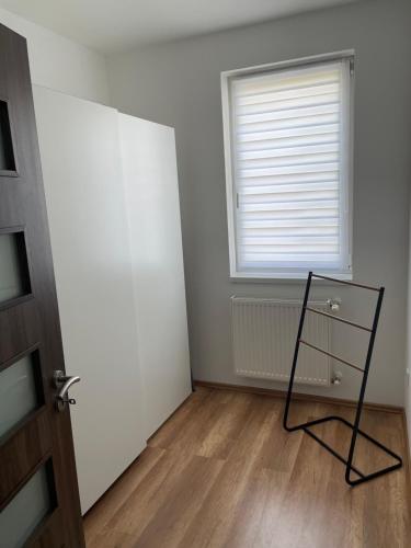 an empty room with a window and a chair at BRL Apartman in Nyíregyháza