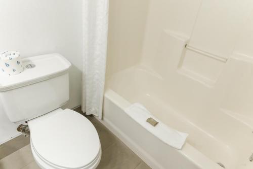 a white bathroom with a toilet and a bath tub at Country Inn & Suites by Radisson, Helen, GA in Helen