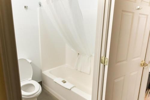 a white bathroom with a toilet and a bath tub at Country Inn & Suites by Radisson, Helen, GA in Helen