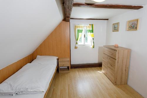 a small bedroom with a bed and a wooden cabinet at Chata Lomnice U Potoka in Lomnice