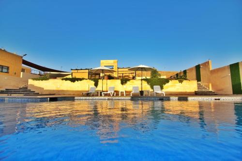 a swimming pool with chairs and umbrellas in a resort at Alma Private Villa in Jerash