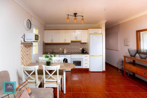 a kitchen with white cabinets and a table and chairs at Tita Apartment Montaña La Data in San Bartolomé