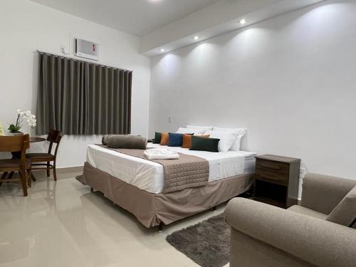 a bedroom with a bed and a table and a chair at FRATELLI PREMIUM HOTEL in Elói Mendes