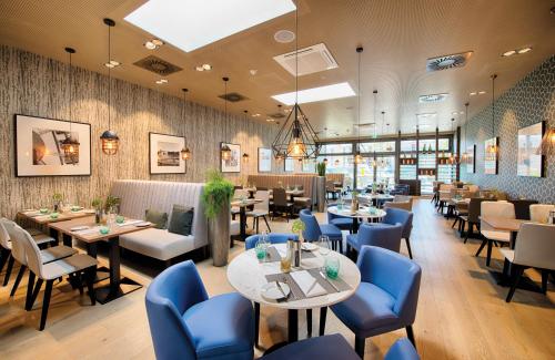 a dining room with tables and blue chairs at Leonardo Hotel Munich City East in Munich