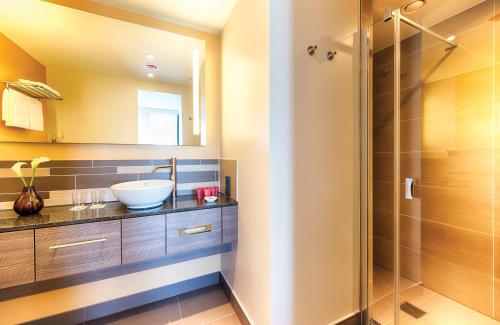 W łazience znajduje się umywalka i prysznic. w obiekcie Leonardo Hotel Munich City East w Monachium