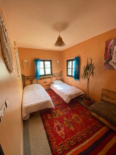 a bedroom with two beds and a rug at Anza surfhouse in Agadir