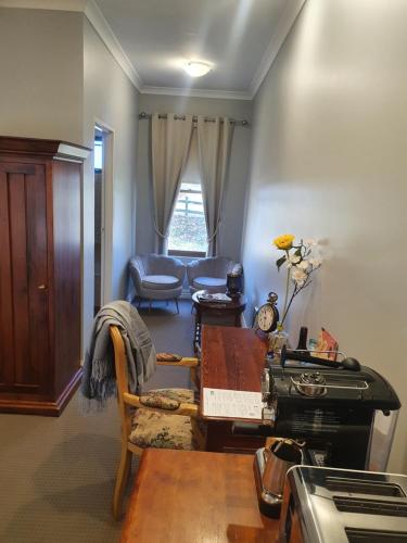 a living room with a table and a chair and a desk at The Lancefield Lodge in Lancefield