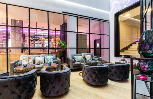 eine Lobby mit Sofas, Tischen und Fenstern in der Unterkunft NYX Hotel Bilbao by Leonardo Hotels in Bilbao