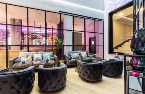 a lobby with couches and tables and windows at NYX Hotel Bilbao by Leonardo Hotels in Bilbao