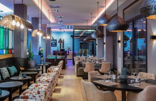 um restaurante com mesas, cadeiras e lustres em NYX Hotel Bilbao by Leonardo Hotels em Bilbao