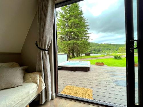 a bedroom with a sliding glass door with a view of a patio at Bonnie Lodge-Lochside Location with Hot Tub in Invergarry