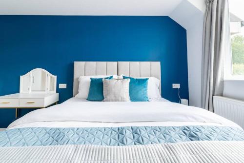 a blue bedroom with a white bed and a blue wall at Dunstan House Luxury Holiday Home with free parking in Oxford