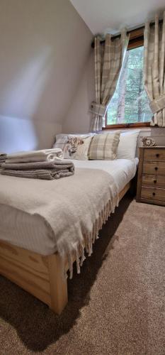 a bedroom with a bed with a dresser and a window at Bonnie Lodge-Lochside Location with Hot Tub in Invergarry