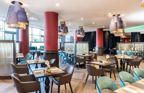 a restaurant with tables and chairs and chandeliers at Leonardo Royal Hotel Venice Mestre in Mestre