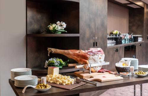 a table with meat on a cutting board and cheese at Leonardo Royal Hotel Venice Mestre in Mestre