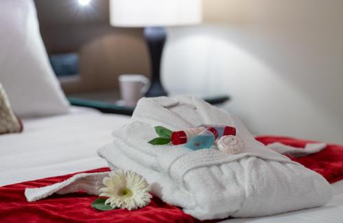 een witte handdoek met bloemen op een bed bij Leonardo Royal Hotel Venice Mestre in Mestre