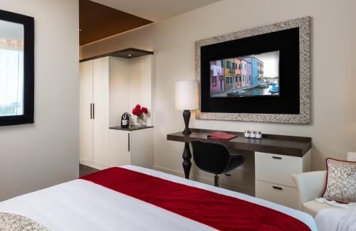 a hotel room with a bed and a desk and a tv at Leonardo Royal Hotel Venice Mestre in Mestre