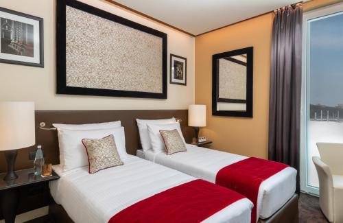 a hotel room with two beds and a window at Leonardo Royal Hotel Venice Mestre in Mestre