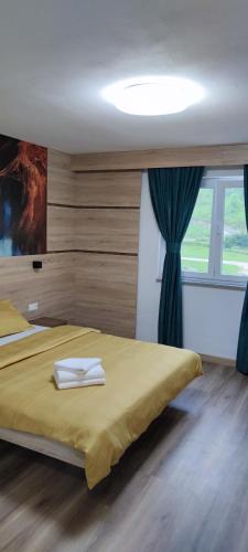 a bedroom with a bed with a yellow blanket and a window at Motel "KULA" in Cazin