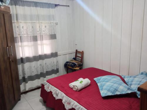 Un dormitorio con una cama roja con una toalla. en Sitio Paraiso Central - Casa Branca, en Rodeio