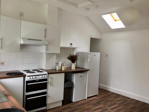 een witte keuken met een fornuis en een koelkast bij Golden Triangle Rooms in Norwich