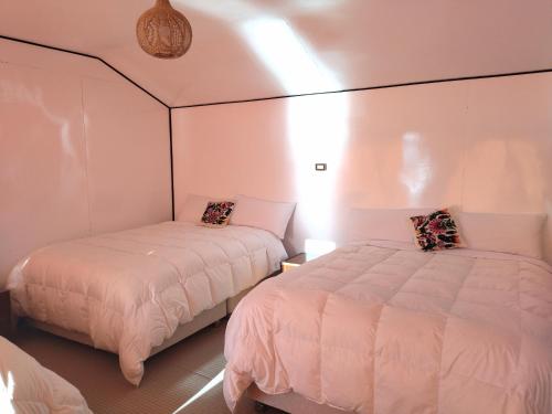 2 Betten in einem Zimmer mit rosa Wänden in der Unterkunft Titicaca Kontiki Lodge Peru in Puno