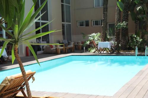 a swimming pool with a chair and a palm tree at Casablanca Suites & Spa in Casablanca