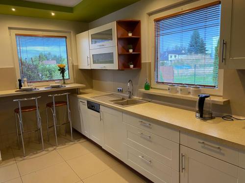 a kitchen with white cabinets and a sink and two windows at 4 Bedroom family house with access to a hot tub in Goczałkowice-Zdrój