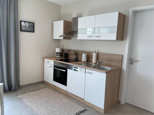 a small kitchen with white cabinets and a sink at Studio - Apartment Steinmetz mit Balkon in Reken
